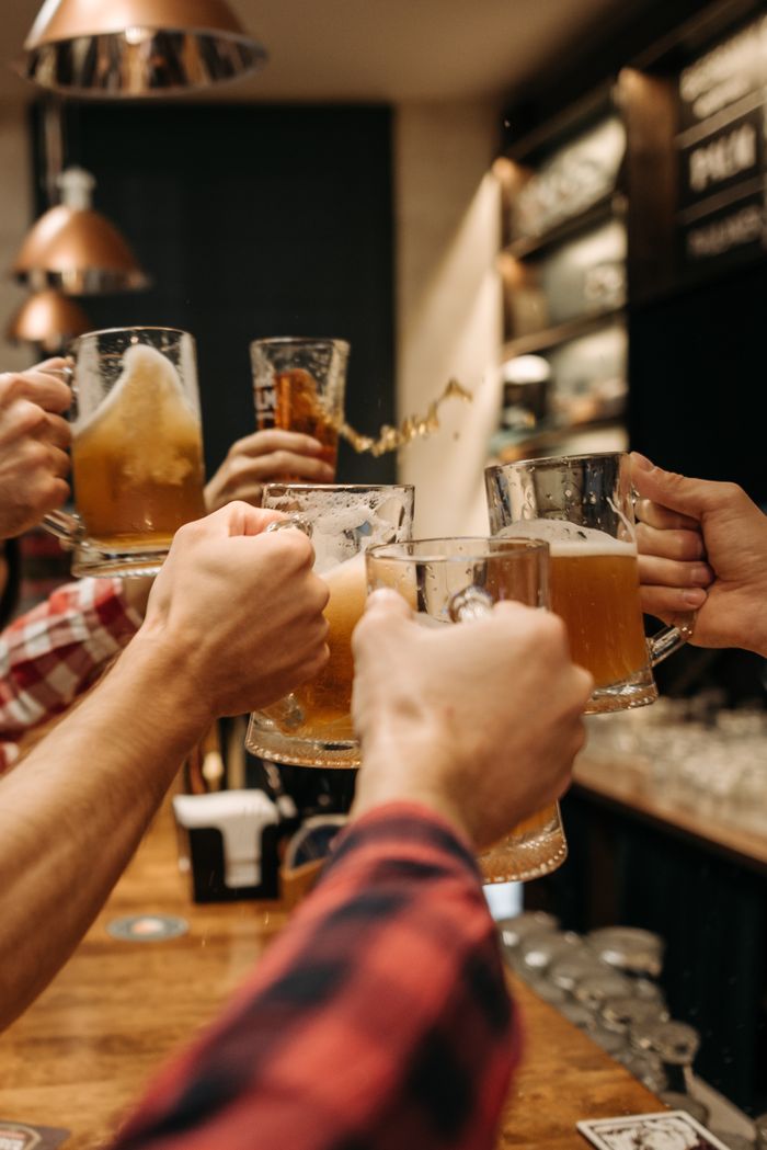 Friends enjoying a toast with beer mugs in a warm pub atmosphere.